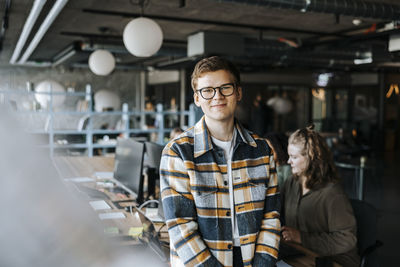 Portrait of smiling young entrepreneur in tech startup office