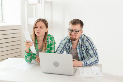 Young man using mobile phone while sitting on table