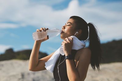 Side view of woman drinking water at beach