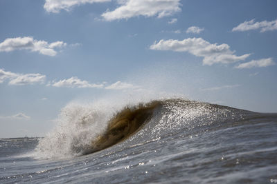 Waves splashing in sea against sky
