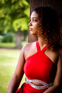 Portrait of young woman standing against trees