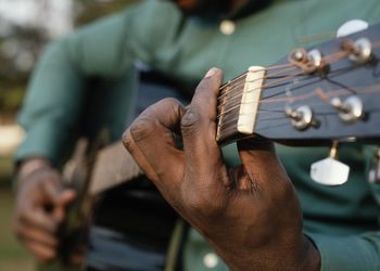 Midsection of man playing guitar