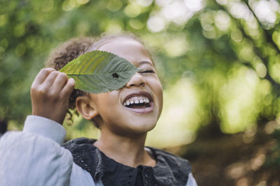 Smiling girl looking through hole in green leaf