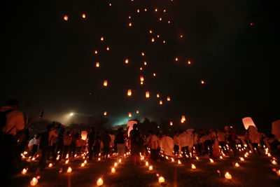 Group of people in illuminated street against sky at night