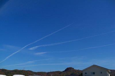 Scenic view of vapor trails over buildings against sky