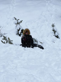 Girl sitting in the snow playing 