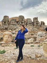Full length of young woman standing against stone wall