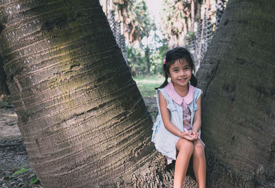 Portrait of smiling girl on tree trunk