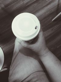 High angle view of hand holding coffee cup on table