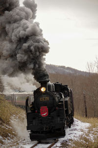 Train on railroad track against sky during winter