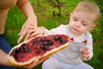 Mother and daughter eat jam bread at a picnic spring