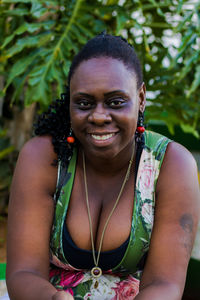 Portrait of smiling mid adult woman sitting against plants