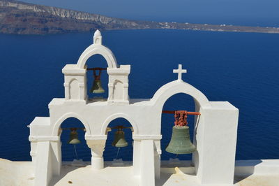 Bells hanging on church against sea