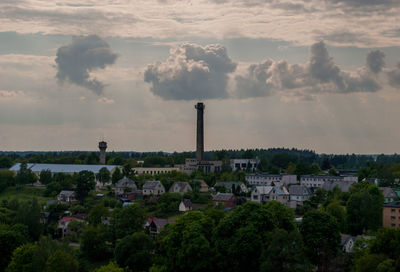 Smoke stack and houses in town against sky