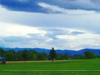 Scenic view of grassy field against cloudy sky