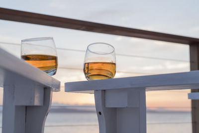 Low angle view of whiskey in glass on table against sky