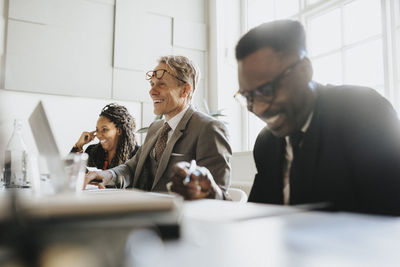 Smiling mature entrepreneur with male and female colleagues during meeting at office