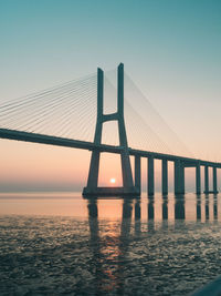 Bridge over sea against sky during sunset