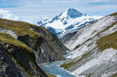 Summit of mount aspiring rises over a narrow canyon, a winding river flows through it