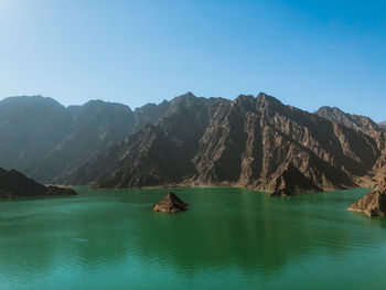 Scenic view of sea and mountains against clear blue sky