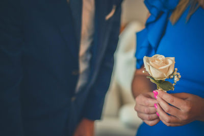 Close-up of woman holding rose while standing by man