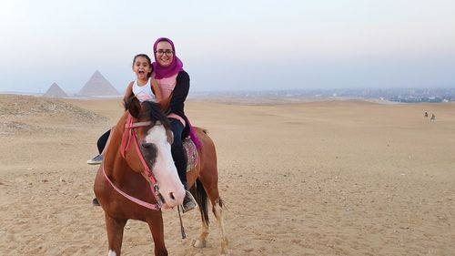 Young mother riding horse at the pyramids