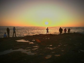 Silhouette of people at beach during sunset