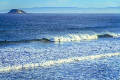 Distant view of person surfing in blue sea