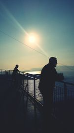 Silhouette of man standing on bridge