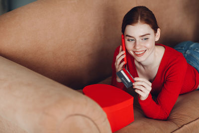 Portrait of a smiling young woman lying down on sofa