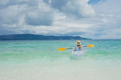 Rear view of woman swimming in sea against sky