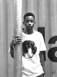 Portrait of young man listening music against wall