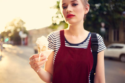 Midsection of woman holding ice cream standing outdoors