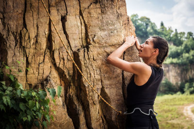Woman with arms raised on cliff against sky