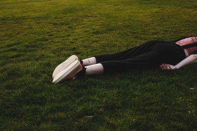 Low section of woman relaxing on grassy field