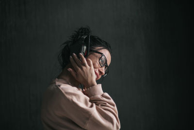 Portrait of young woman standing against black background