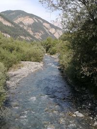 Scenic view of river by mountains against sky