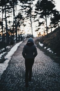 Rear view of woman walking on snow covered road