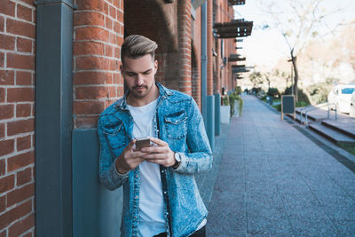 Young man using mobile phone standing in city