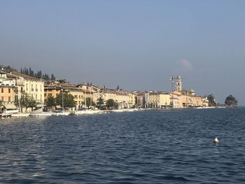 Buildings by sea against clear sky
