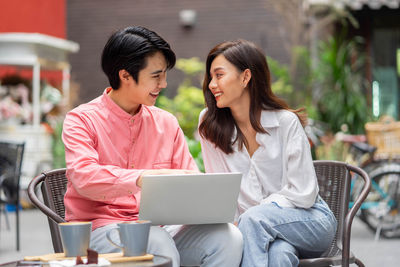 Friends using laptop while sitting on table