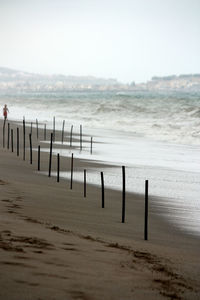 Wooden posts on beach against clear sky