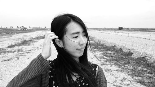 Close-up of young woman on beach against sky