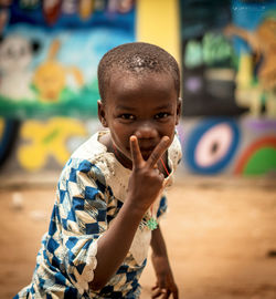 Portrait of boy gesturing peace sign in village