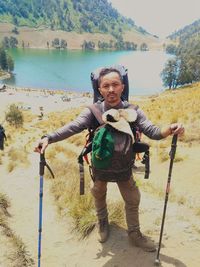 Portrait of young man holding camera while standing on land