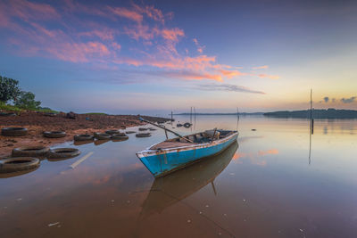 Boats moored in marina at sunset