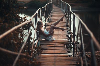 Woman sitting on wooden footbridge