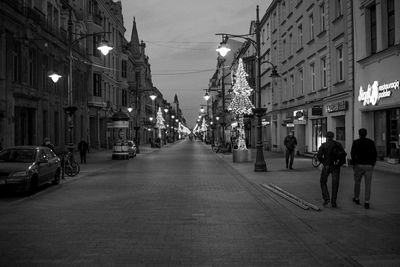 People on illuminated street amidst buildings in city at night