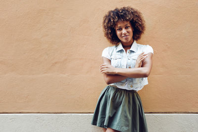 Portrait of mid adult woman with arms crossed standing by wall