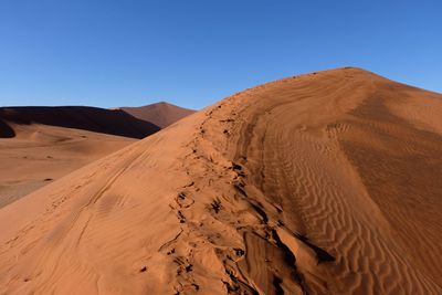 Sand dunes in desert against clear sky